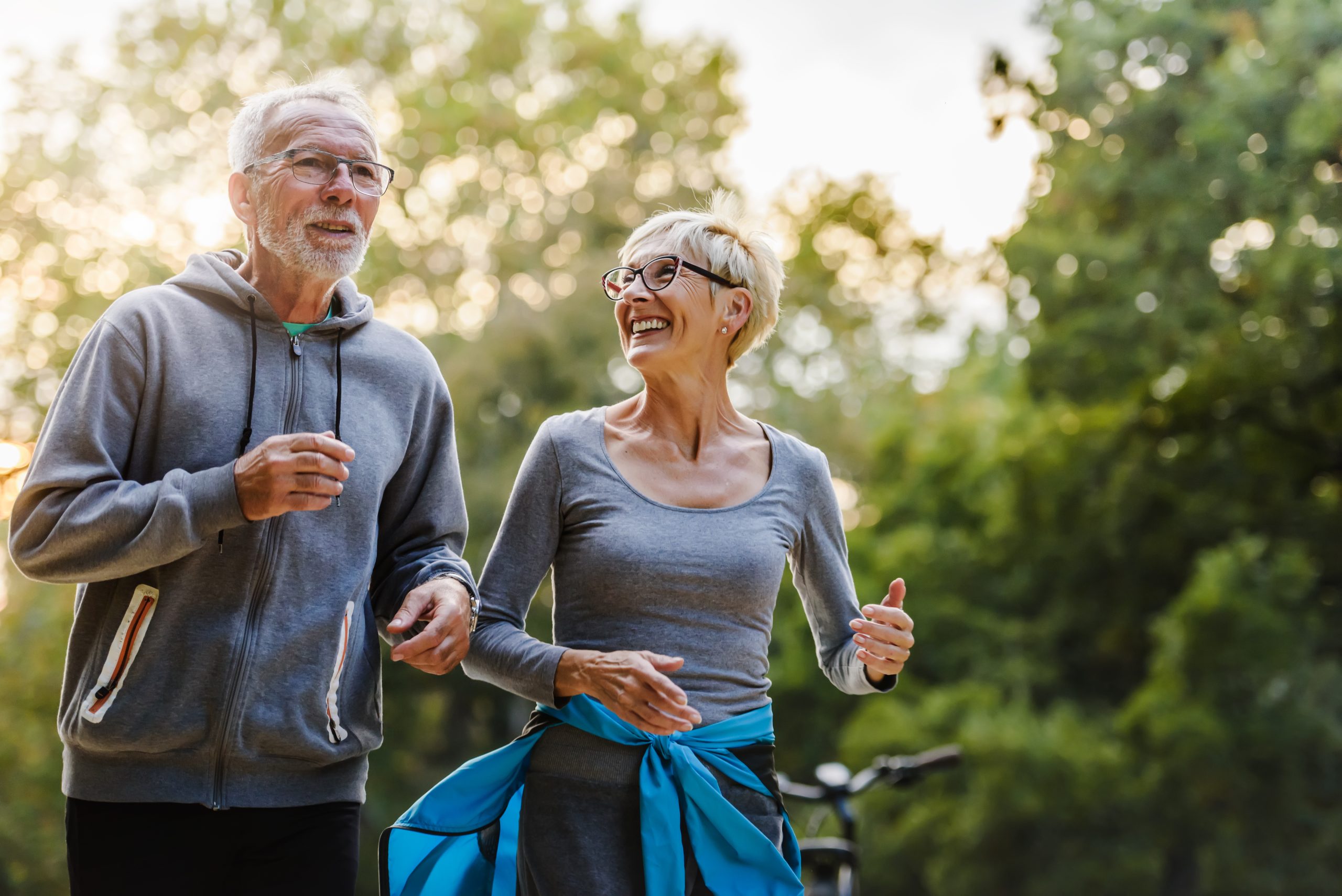 man and woman smiling and walking in the forest